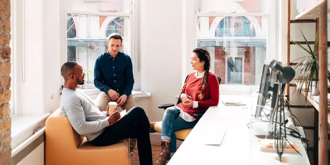 Three colleagues talking together in a bright office